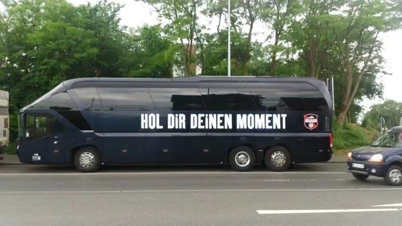 Ein blauer Bus mit der Aufschrift „Hol dir deinen Moment“, 02elf Travel GmbH & Co KG