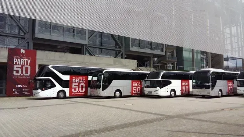 Vor einem Gebäude parkt eine Reihe Busse. 02elf Travel GmbH & Co KG