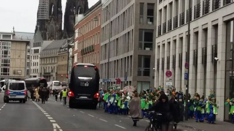 Eine Gruppe von Menschen geht eine Straße vor einem großen Gebäude entlang.
