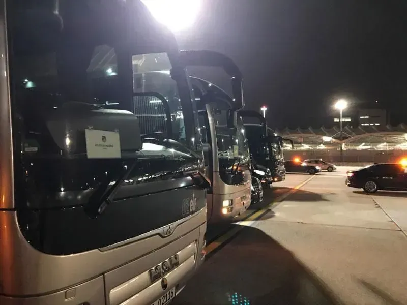 Eine Reihe von Bussen stehen nachts auf einem Parkplatz, 02elf Travel GmbH & Co KG