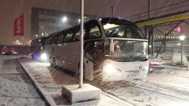 Ein Bus steht nachts auf einem verschneiten Parkplatz. 02elf Travel GmbH & Co KG