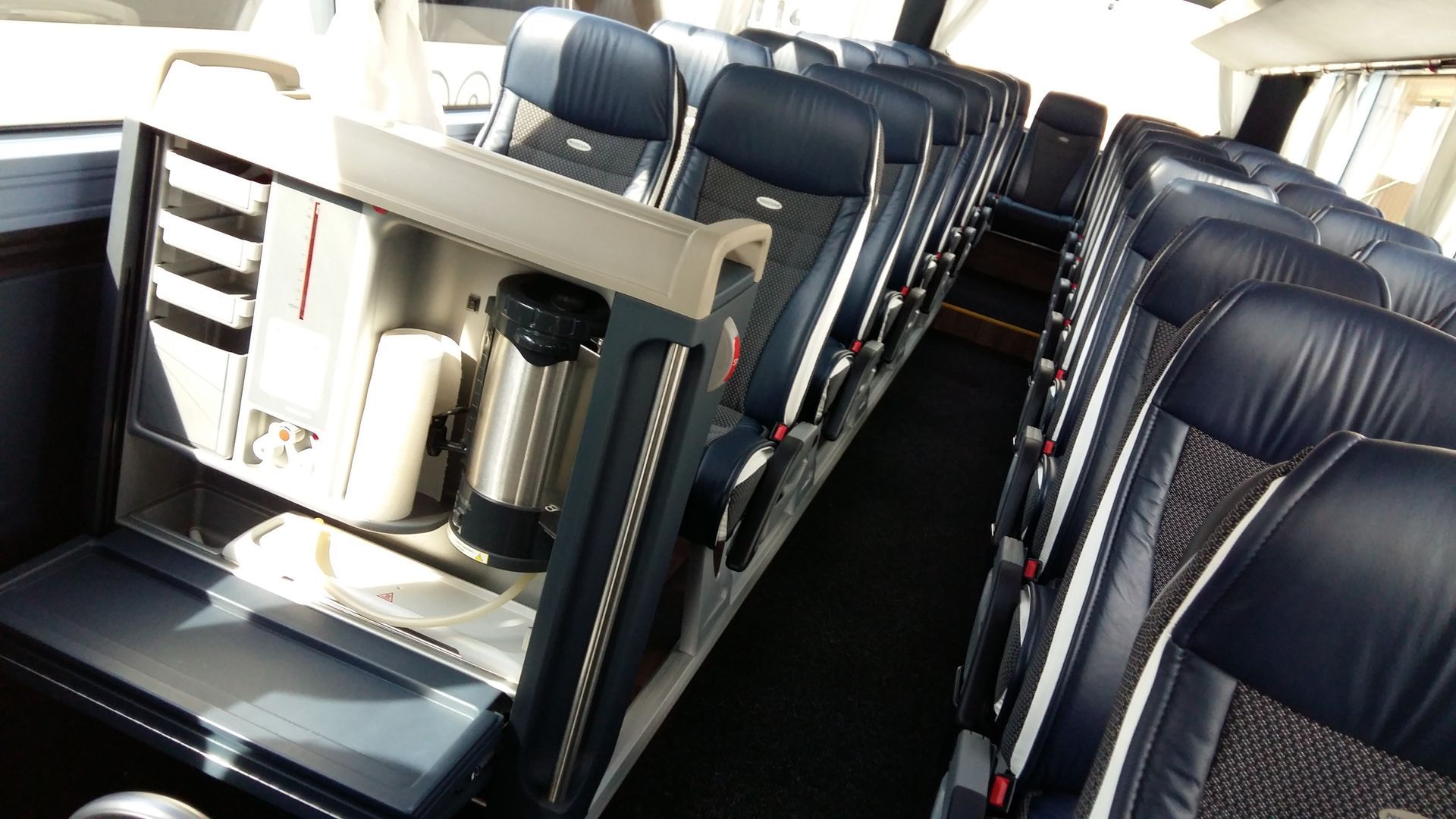 Leerer Zugwaggon mit Reihen blauer Sitze und Gangplätzen im hellen Sonnenlicht