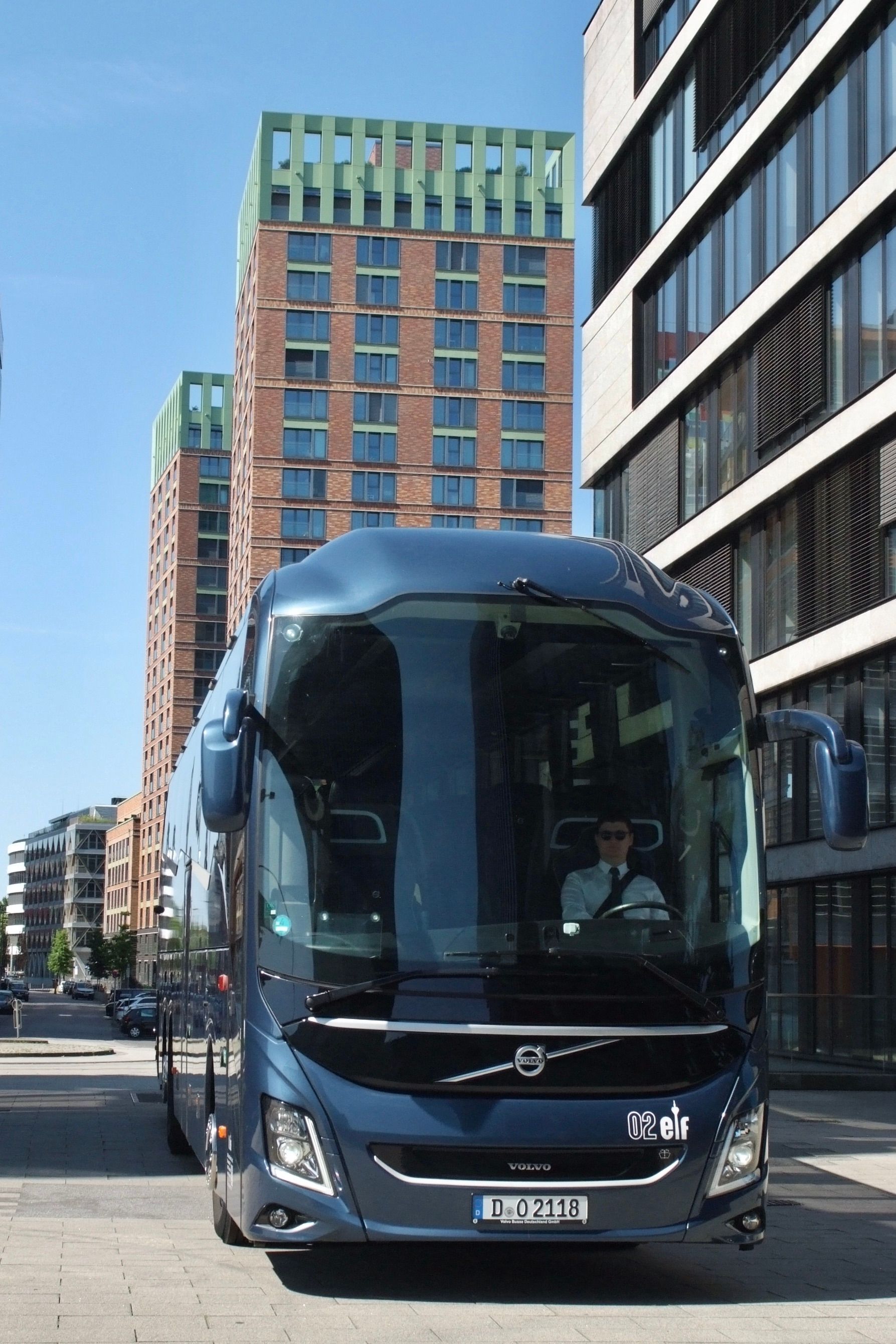 Ein blauer Stadtbus auf einer Straße neben modernen Gebäuden unter klarem Himmel