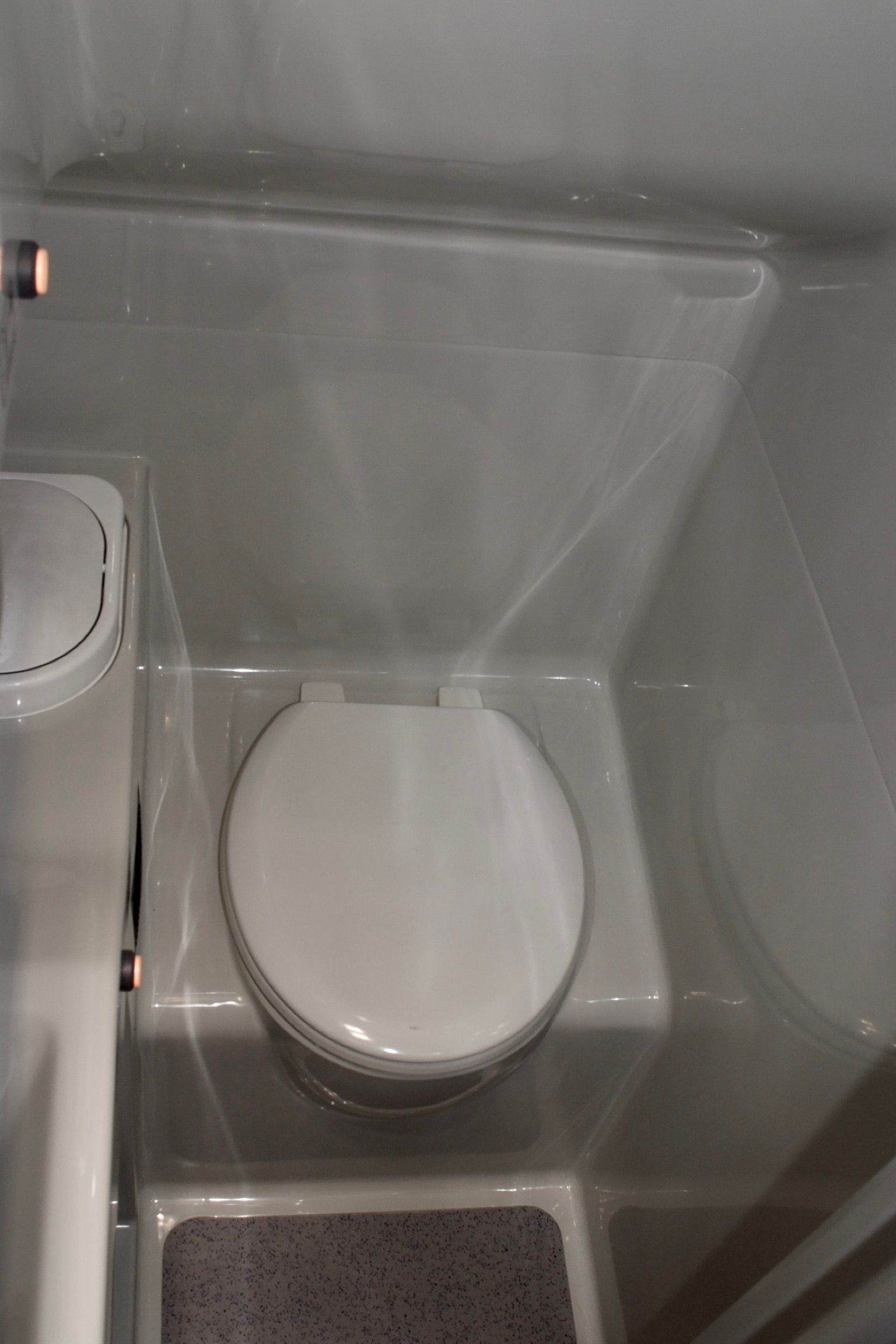 Kleines Badezimmer mit Toilette und durchsichtigem Duschvorhang aus Kunststoff.