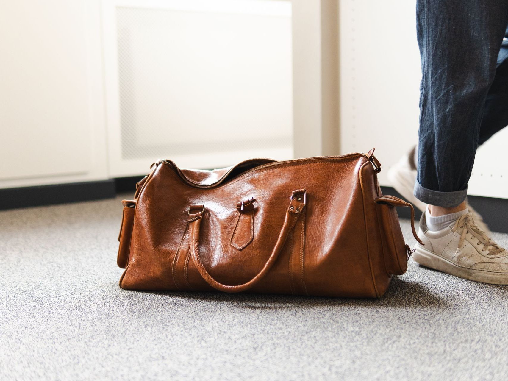 eine Braune Reisetasche steht auf dem Boden