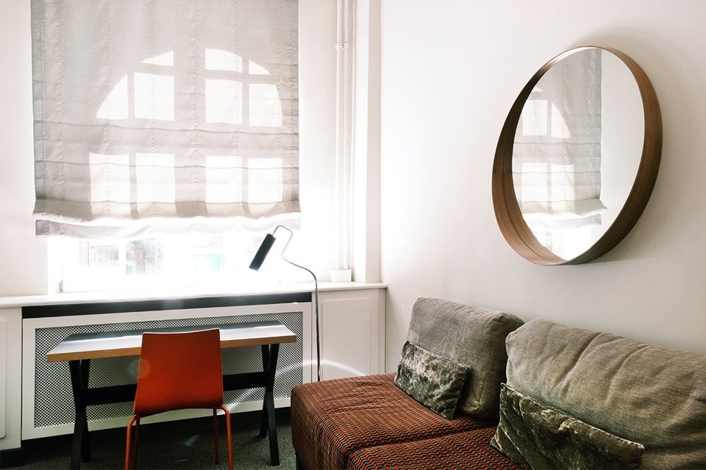 Ein Wohnzimmer mit einer Couch, einem Schreibtisch und einem runden Spiegel