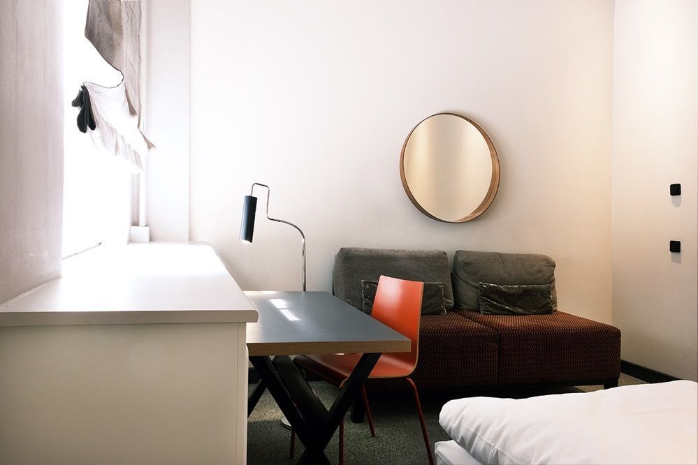 Ein Hotelzimmer mit Couch, Schreibtisch, Stuhl und Spiegel.