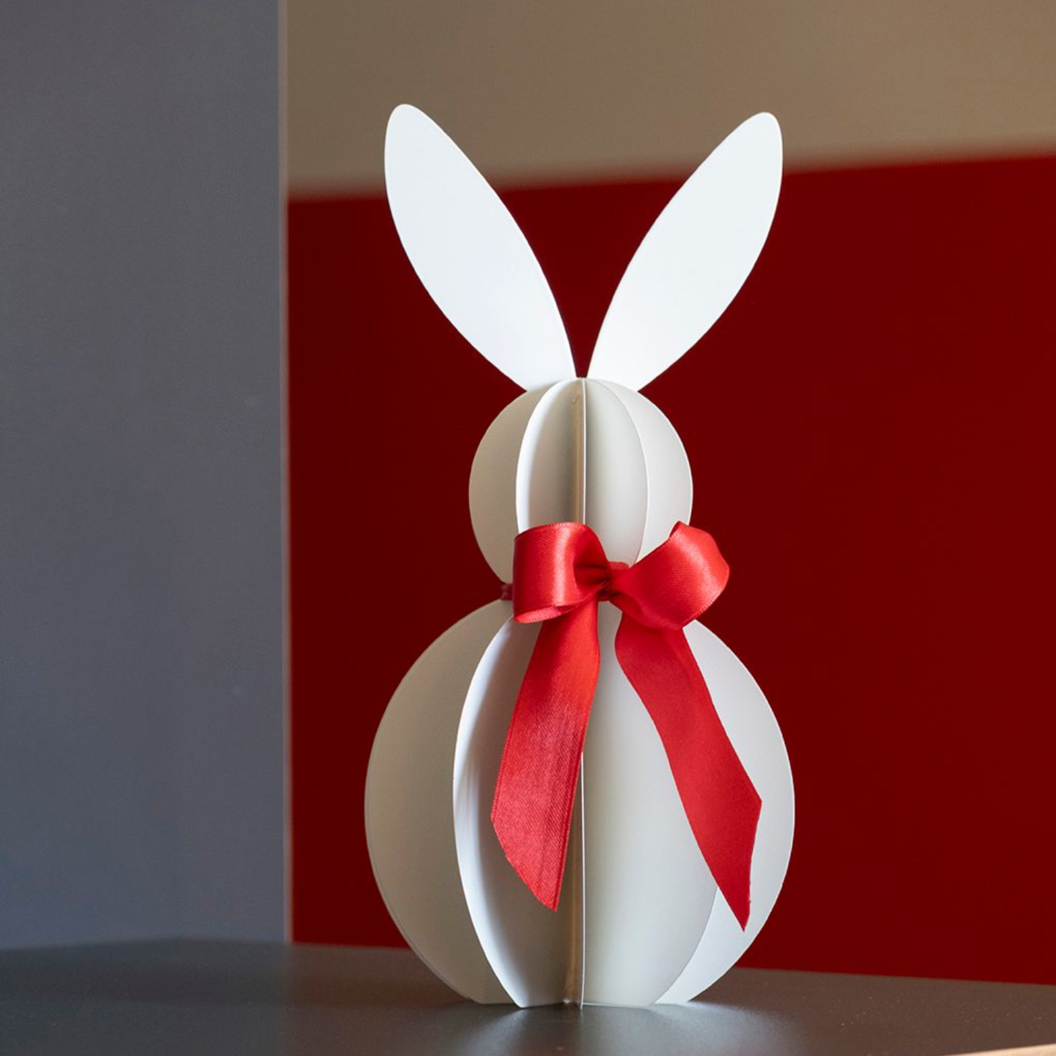 Eine Frau sitzt an einem Schreibtisch vor einem Fenster und arbeitet am Laptop. Hinter ihr steht ein großer Strauß Blumen.