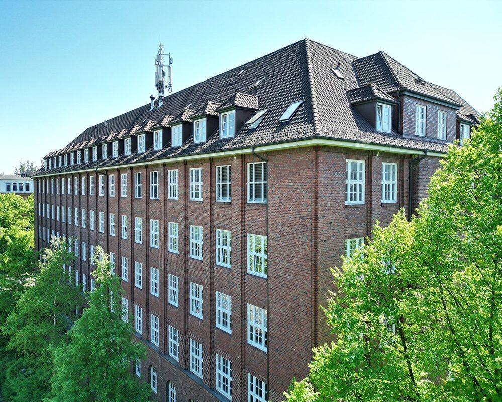 Eine Luftaufnahme eines großen Backsteingebäudes, umgeben von Bäumen