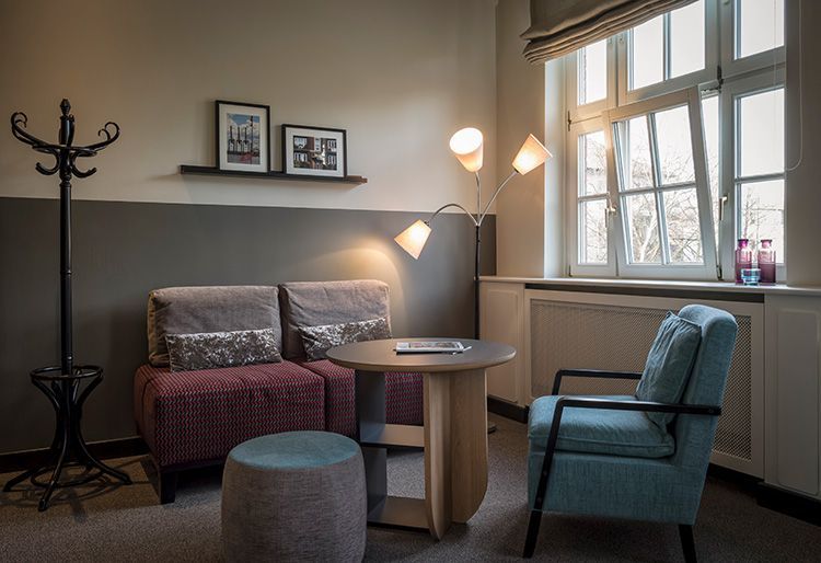 Ein Wohnzimmer mit Couch, Sessel, Tisch und Fenster.