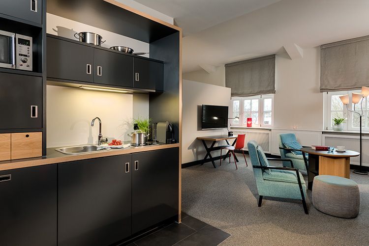 Eine Küche mit schwarzen Schränken und einer Spüle in einem Wohnzimmer.