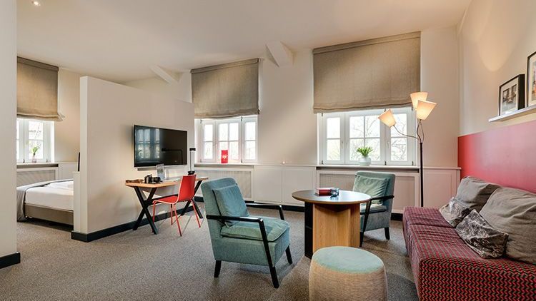 Loft-Apartment - ein Schreibtisch, ein Fernseher, ein Hocker, zwei Sessel, ein Sofa und ein Lounge-Tisch
