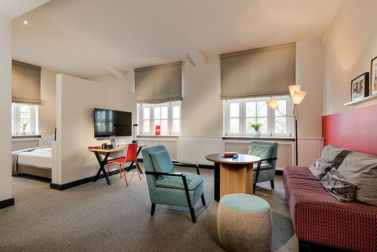 Ein Hotelzimmer mit Couch, Stühlen, Tisch und Fernseher.