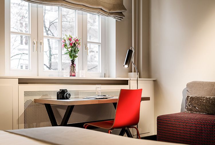 Ein Schlafzimmer mit einem Schreibtisch und einem Stuhl vor einem Fenster.