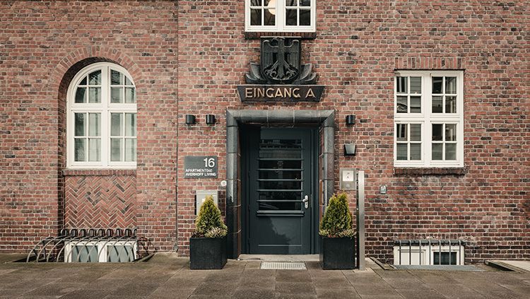 Die Vorderseite eines Backsteingebäudes mit einer schwarzen Tür und schwarzen Fenstern.