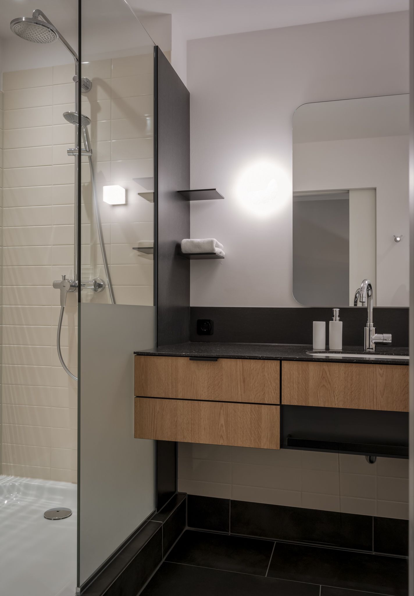 Ein Badezimmer mit ebenerdiger Dusche, Waschbecken und Spiegel.