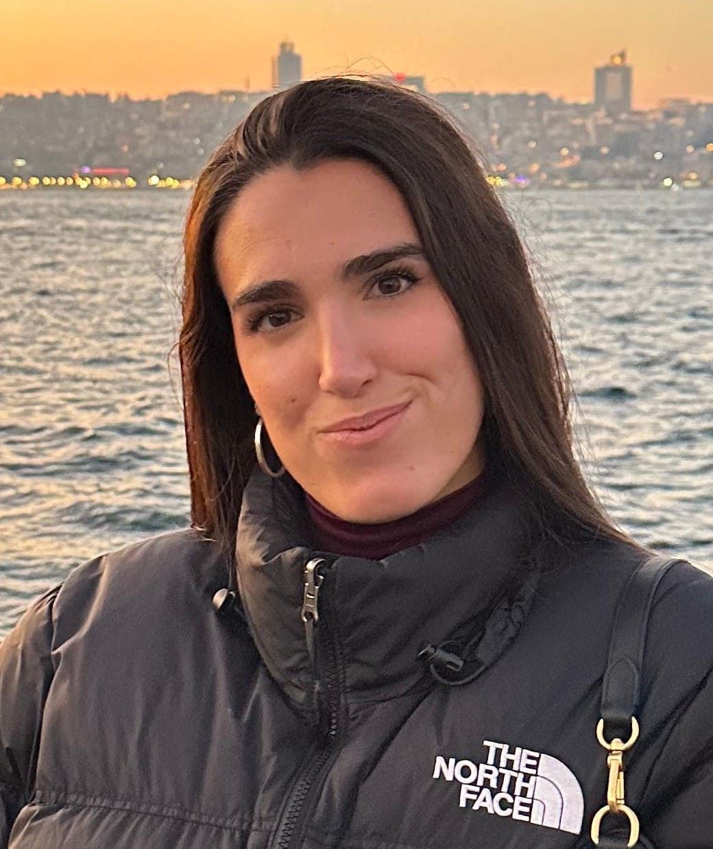 Persona con blazer azul claro, de espaldas a la cámara, con cabello trenzado contra un cielo azul con nubes tenues.