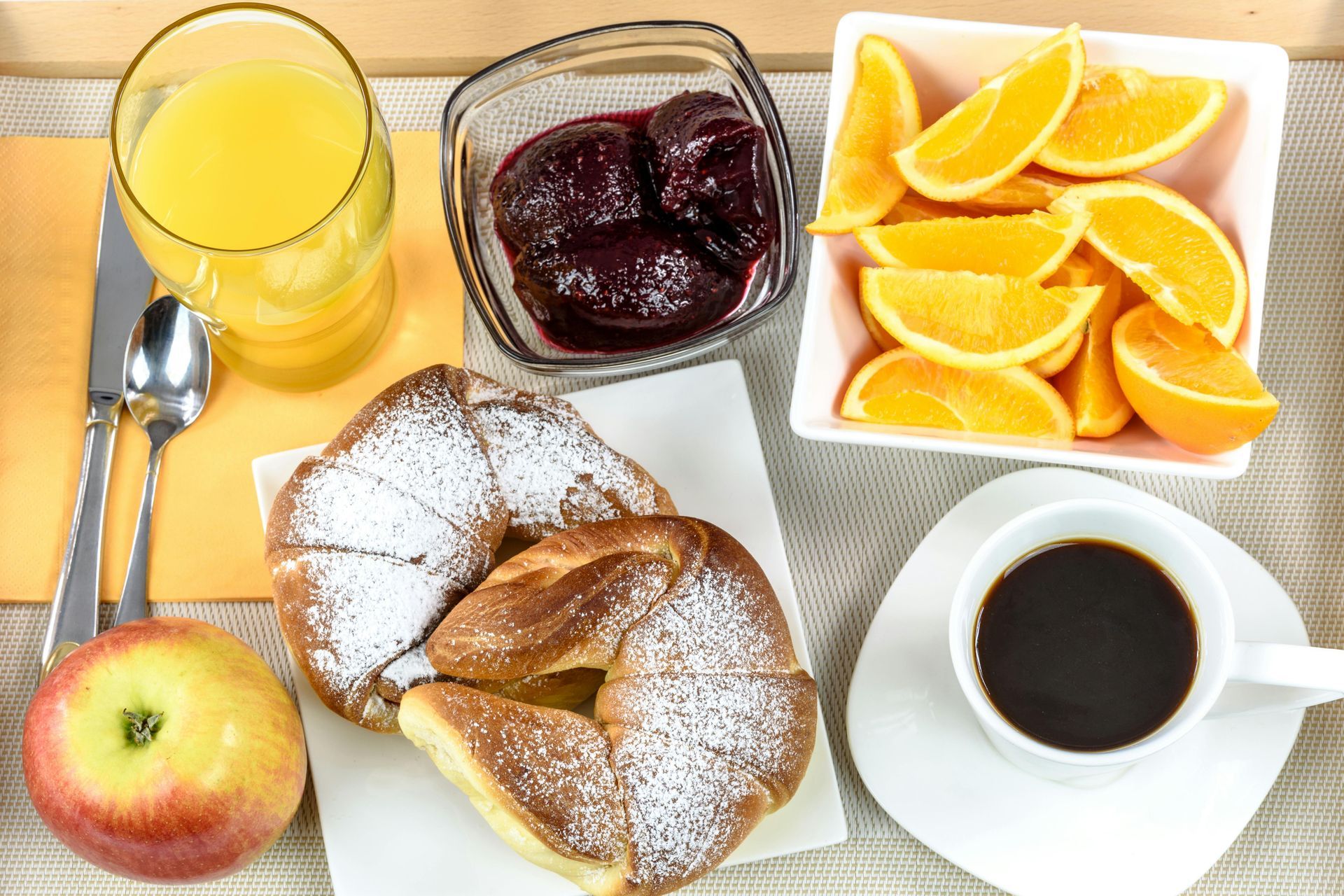 A table topped with a cup of coffee a croissant a bowl of fruit and a glass of orange juice