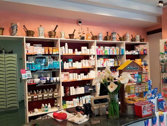 Una farmacia con un jarrón de flores en el mostrador.