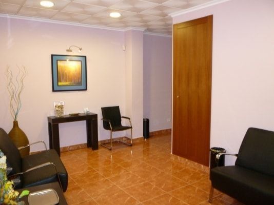 Una sala de espera con un sofá y sillas y un cuadro en la pared.
