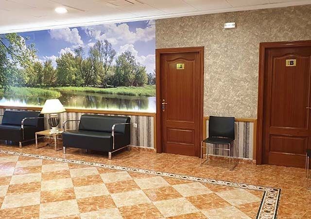 Una sala de espera con un sofá, sillas y un cuadro en la pared.