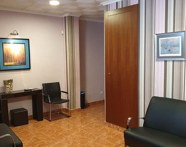 Una sala de espera con un sofá, una silla, una mesa y una puerta.