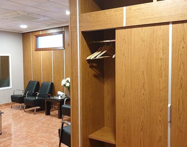 Una sala de espera con sillas y un armario con ropa colgada.