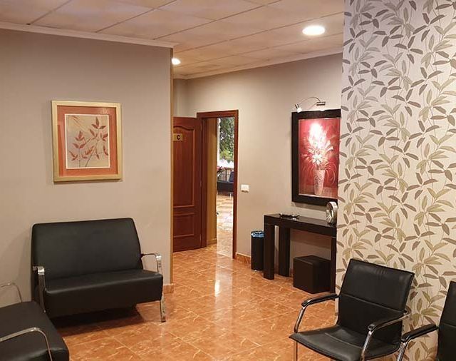 Una sala de espera con un sofá y sillas y un cuadro en la pared.
