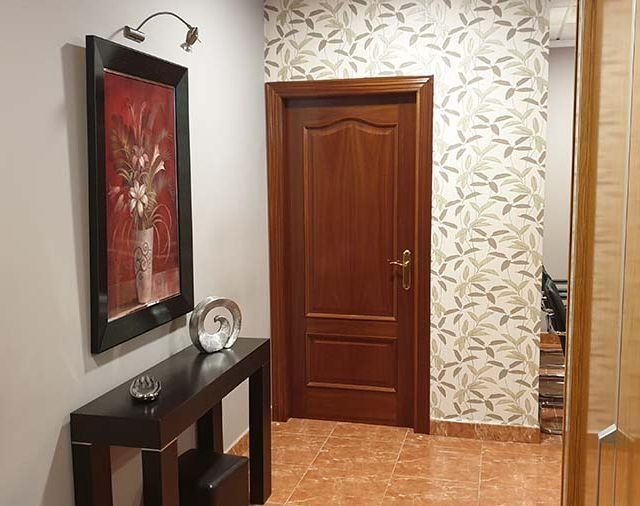 Un pasillo con una mesa y un cuadro en la pared.