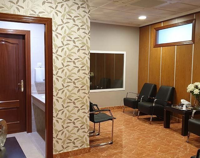Una sala de espera con sillas, mesas y una ventana.