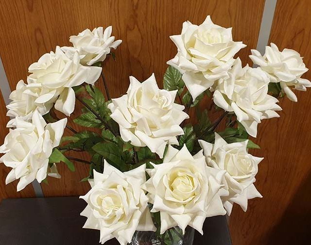 Un ramo de rosas blancas en un jarrón sobre una mesa.