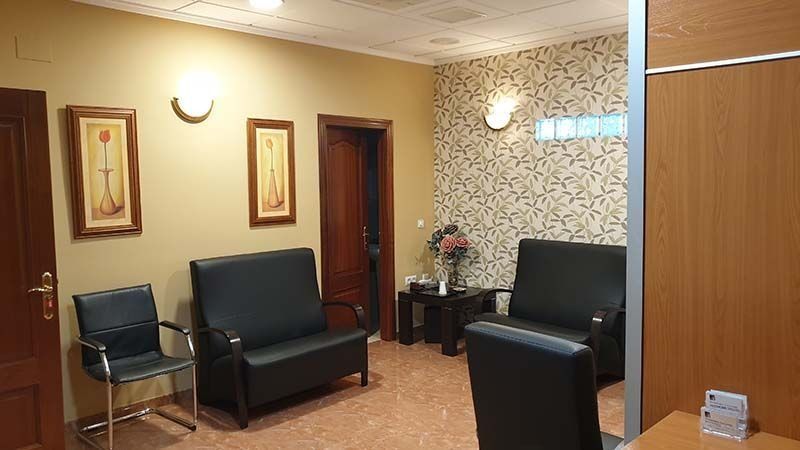 Una sala de espera con un sofá, sillas y una mesa.