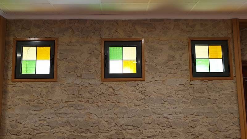 Tres vidrieras cuelgan de una pared de piedra.