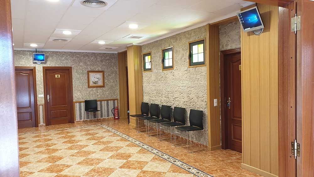 Un largo pasillo con una fila de sillas y un extintor de incendios.