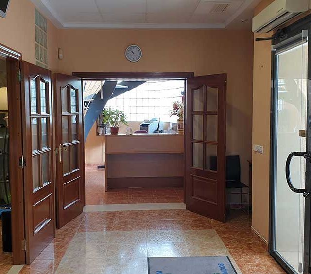 Un pasillo con puertas de madera y un reloj en la pared.