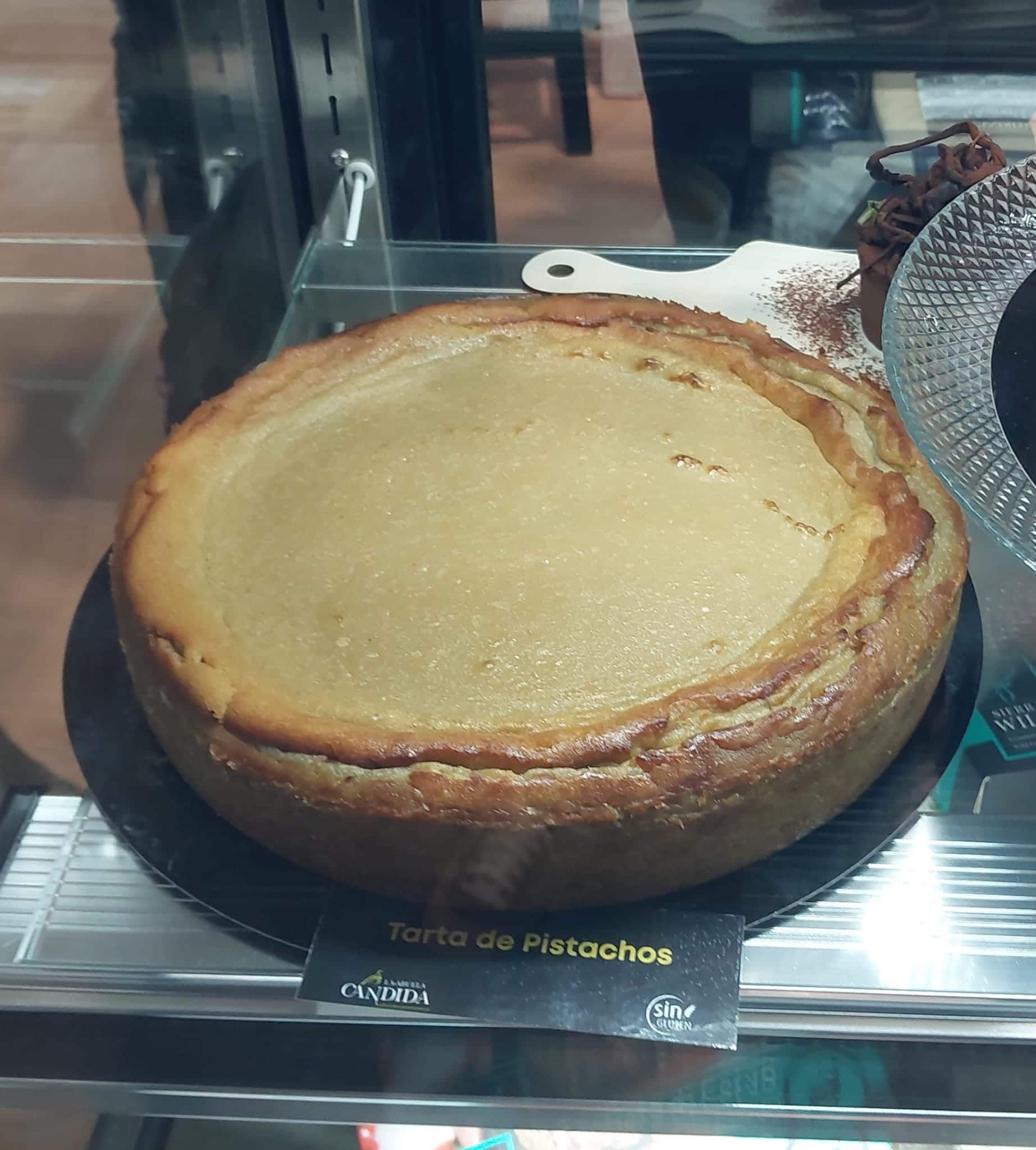 Tarta de queso con base marrón claro, sobre un plato negro. La etiqueta dice 
