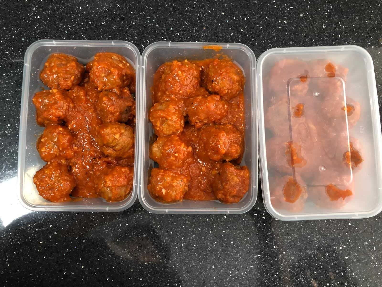 Tres recipientes de plástico con albóndigas en salsa roja; uno con menos albóndigas.