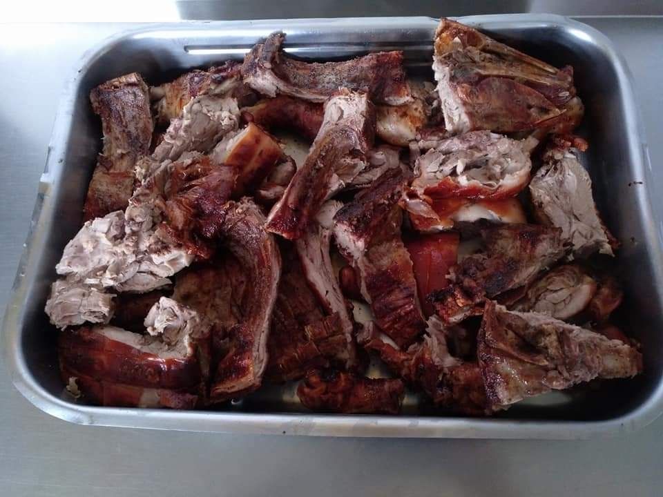 Trozos de cerdo asados ​​en bandeja metálica; carne dorada y crujiente.