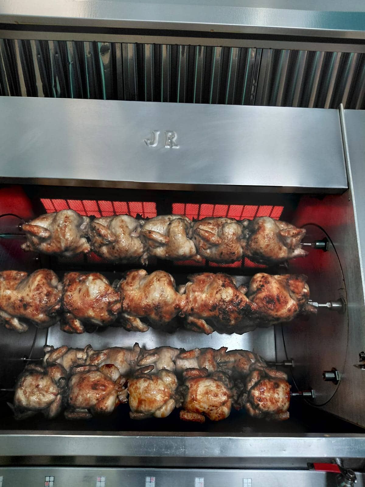 Horno asador con filas de pollos asados.