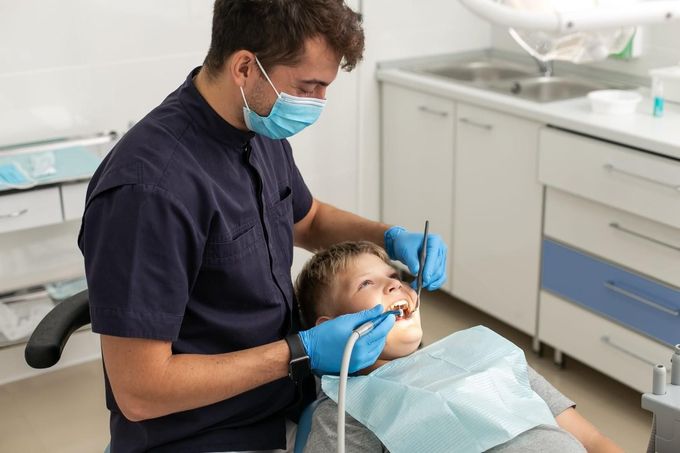 Modelo dental con instrumentos de ortodoncia dispuestos a su alrededor sobre un fondo turquesa.