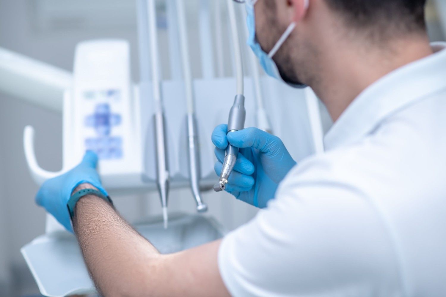 Dentista con guantes y mascarilla examinando a un paciente en una clínica dental.