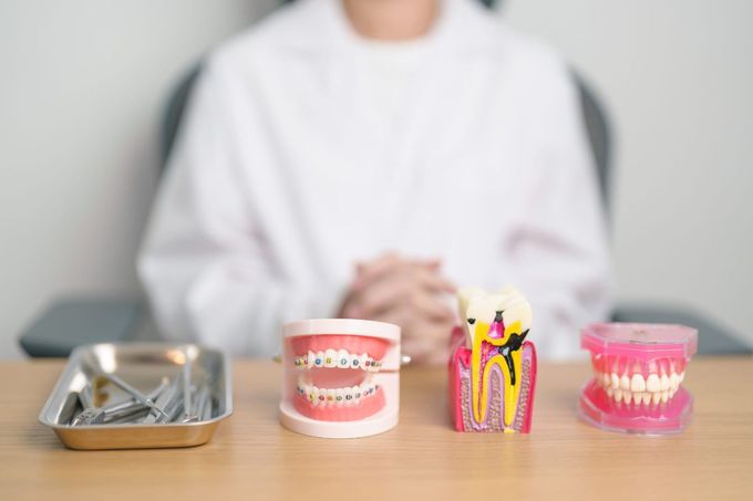 Modelos y herramientas dentales sobre una mesa con una persona borrosa al fondo.