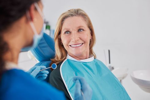 Dentista y asistente examinando los dientes de un paciente con guantes en una luminosa sala de consulta.