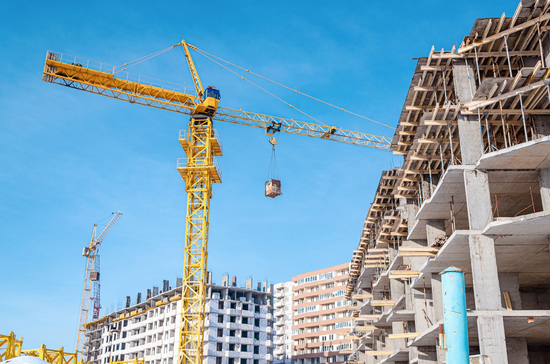 Baustelle mit gelben Kränen und unfertigen Gebäuden unter blauem Himmel