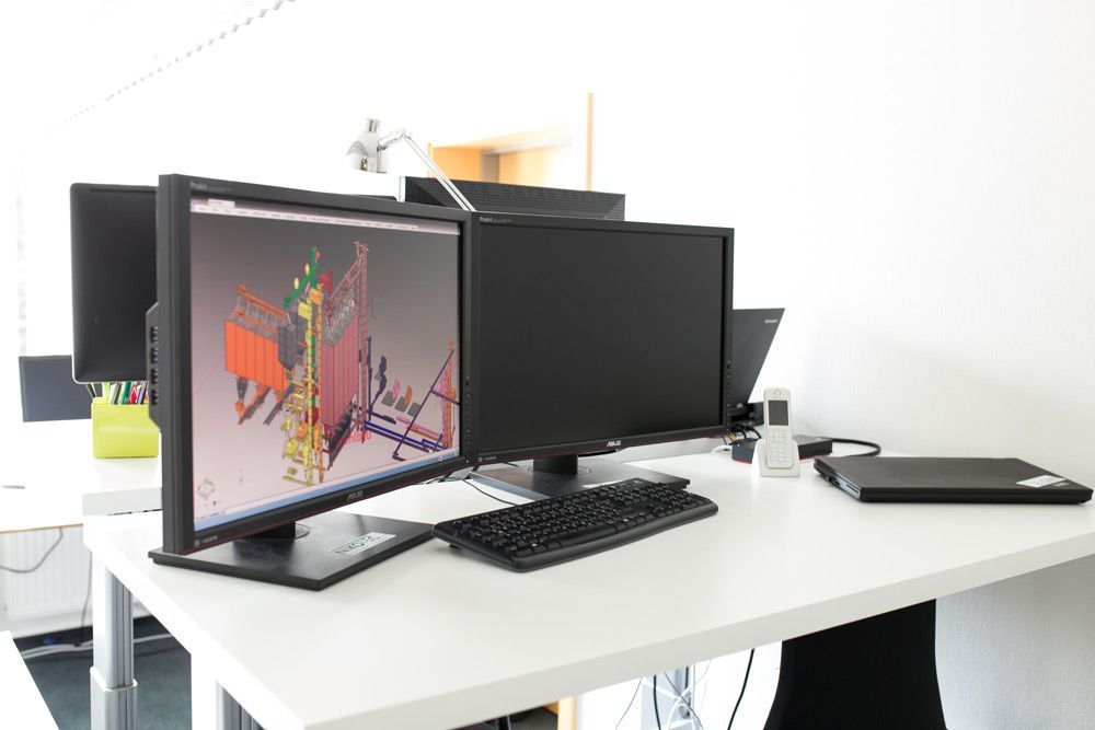 Moderner Bürotisch mit mehreren Monitoren, Tastatur, Maus und Laptop auf einem weißen Tisch