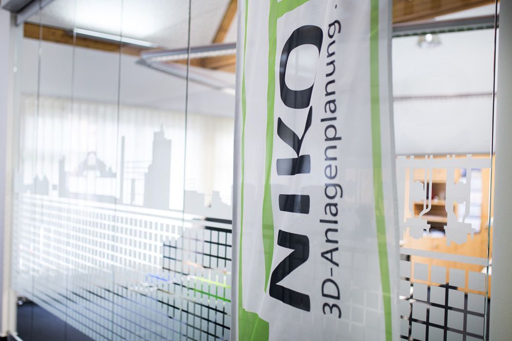 Glasbüro mit einem vertikalen grünen Banner mit der Aufschrift „Niko 3D-Anlagenplanung“