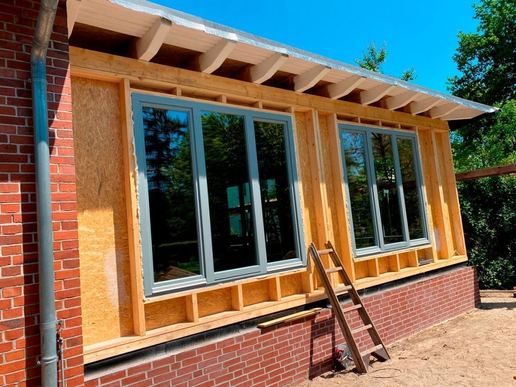 Die Fassade des Backsteinhauses wird teilweise renoviert; ein neues Holzfachwerk und große Fenster befinden sich im Bau.
