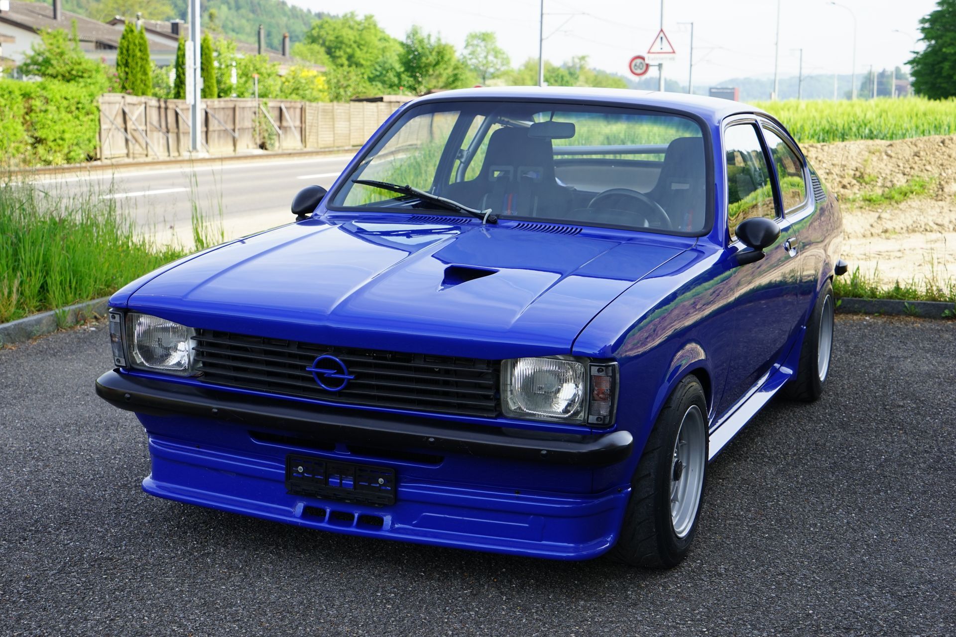 Ein rosa Cadillac steht auf einer Schotterstrasse. Foto von der JoCar Carrosserie- und Autospritzwerk AG
