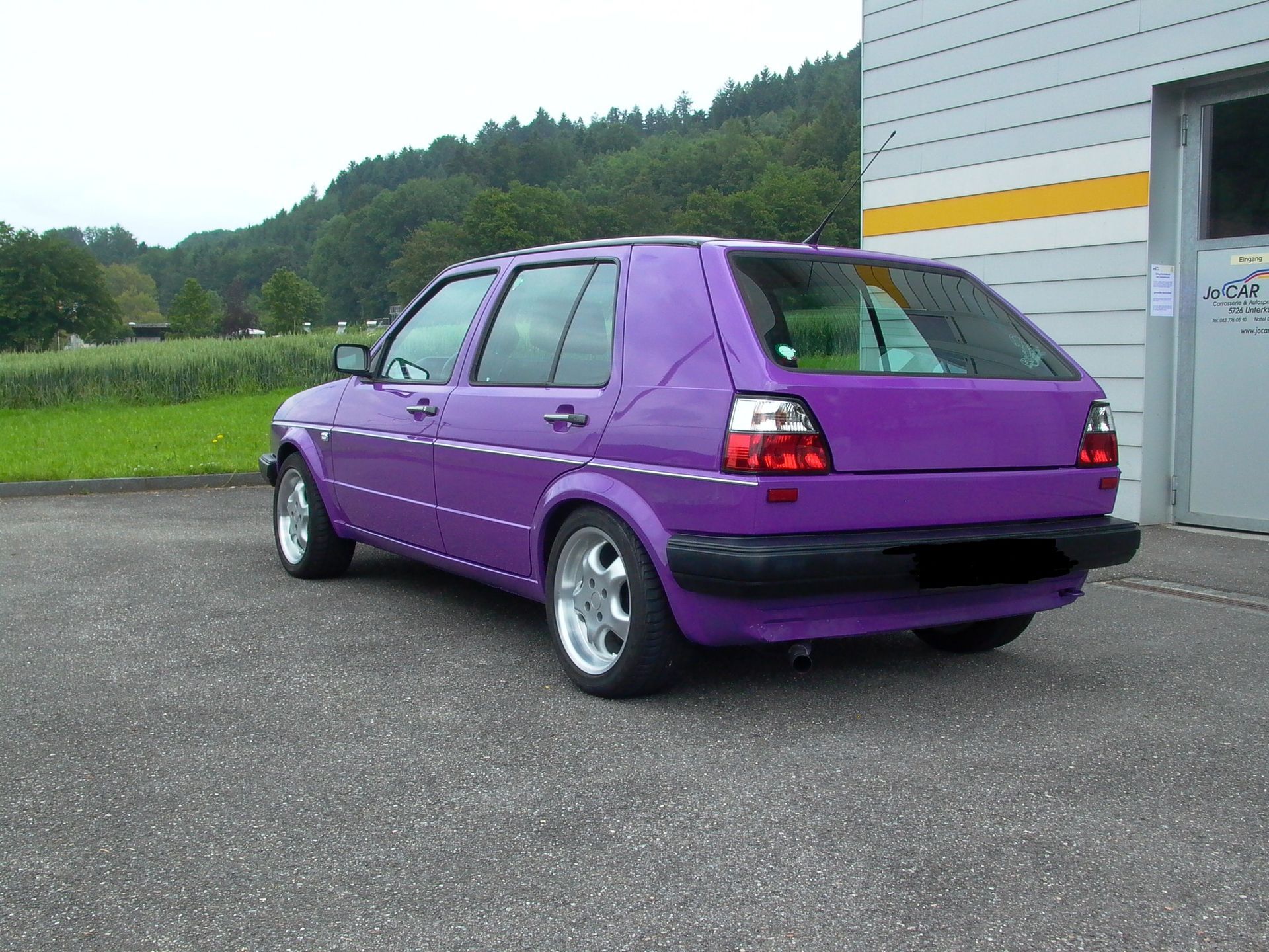Ein orangefarbenes Auto wird lackiert. Foto von der JoCar Carrosserie- und Autospritzwerk AG