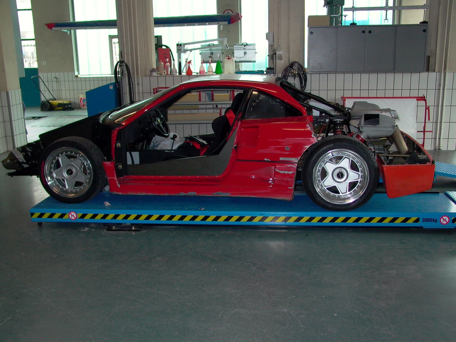 Ein rotes Auto steht auf einem Lift. Foto von der JoCar Carrosserie- und Autospritzwerk AG